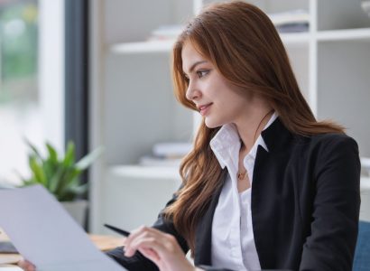 Elegant businesswoman analyzes financial reports at her office desk inside..